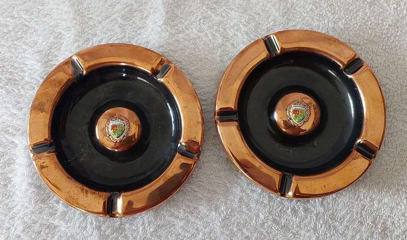 A lot of two vintage red copper ashtrays with small porcelain SA coat of arms in centre
