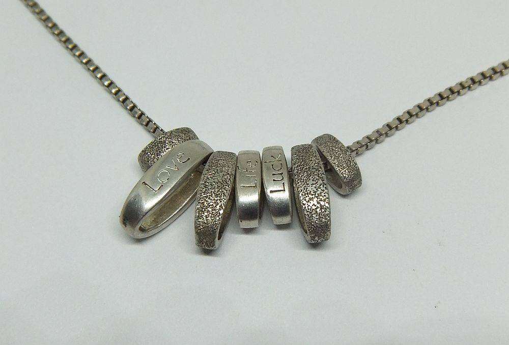 A quality sterling silver necklace with unique "Love, Life, Luck" theme pendants in great condition