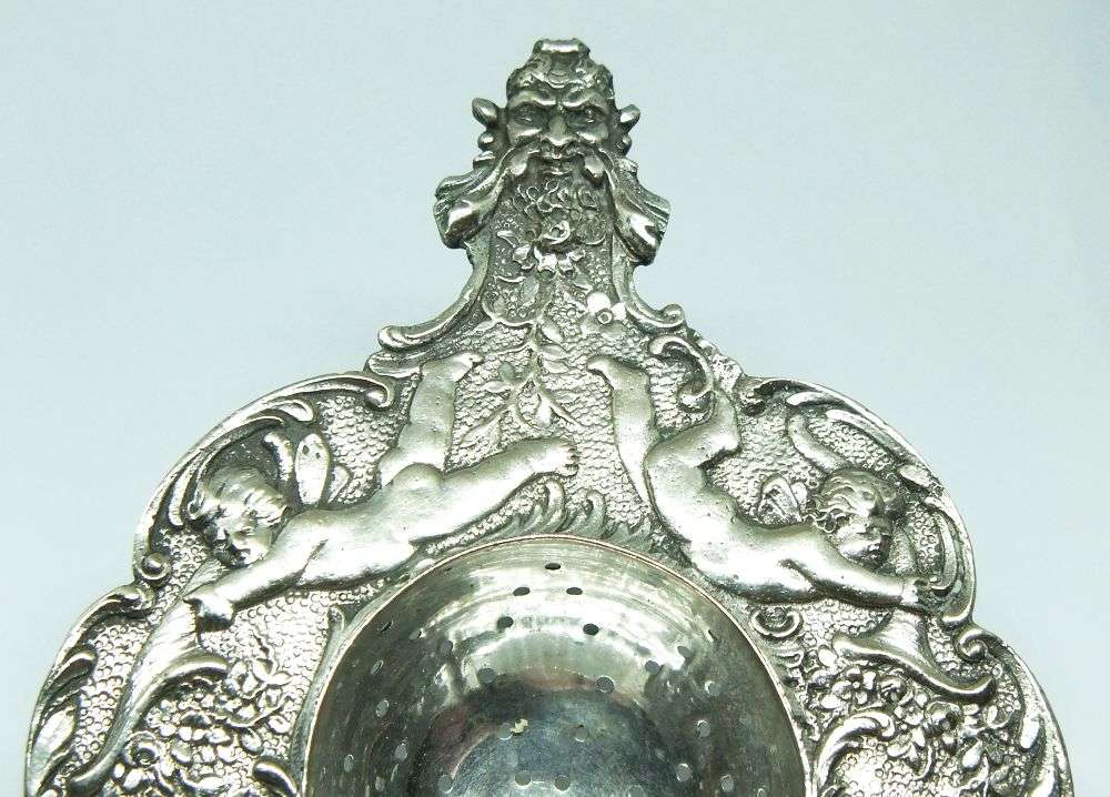 WOW !! A BEAUTIFUL ANTIQUE TEA STRAINER DECORATED WITH CHERUBS STAMPED WITH UNKNOWN MARKINGS