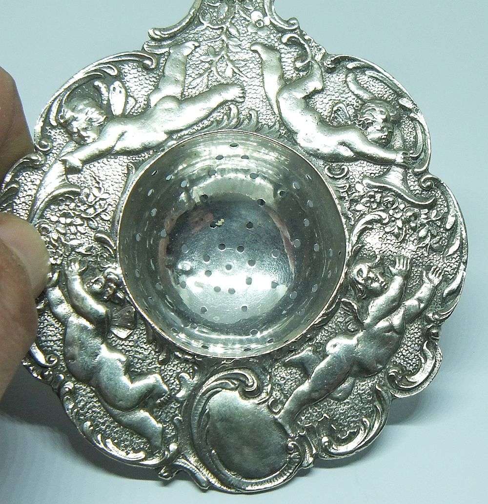 WOW !! A BEAUTIFUL ANTIQUE TEA STRAINER DECORATED WITH CHERUBS STAMPED WITH UNKNOWN MARKINGS
