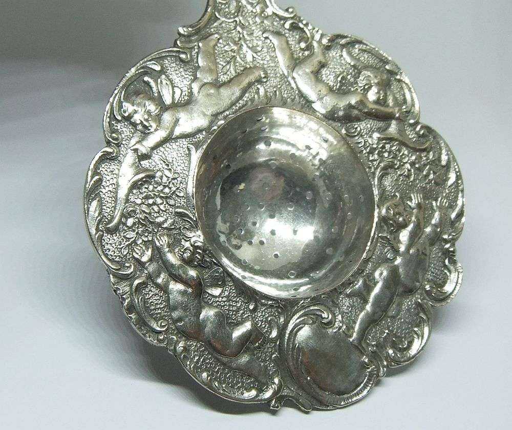 WOW !! A BEAUTIFUL ANTIQUE TEA STRAINER DECORATED WITH CHERUBS STAMPED WITH UNKNOWN MARKINGS
