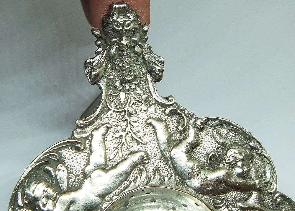 WOW !! A BEAUTIFUL ANTIQUE TEA STRAINER DECORATED WITH CHERUBS STAMPED WITH UNKNOWN MARKINGS