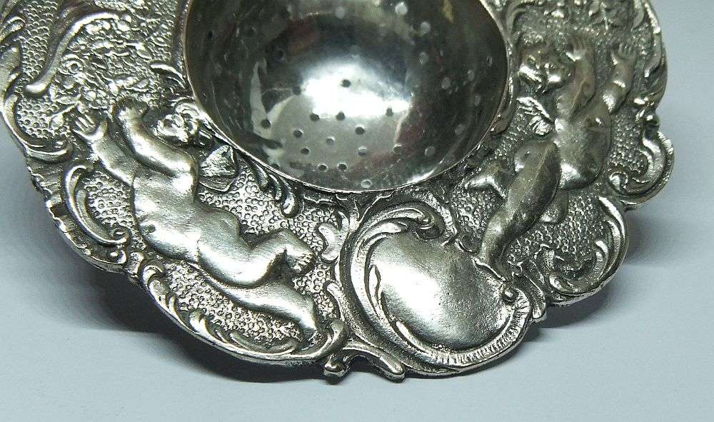 WOW !! A BEAUTIFUL ANTIQUE TEA STRAINER DECORATED WITH CHERUBS STAMPED WITH UNKNOWN MARKINGS
