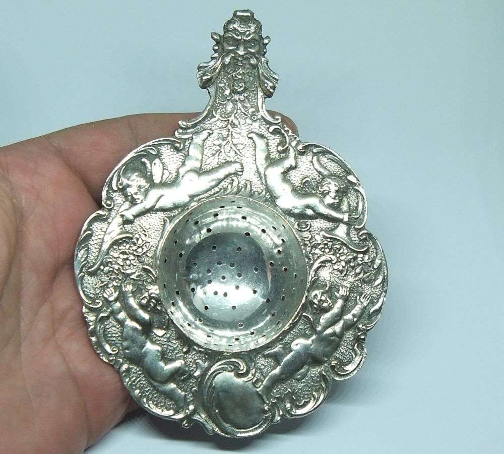 WOW !! A BEAUTIFUL ANTIQUE TEA STRAINER DECORATED WITH CHERUBS STAMPED WITH UNKNOWN MARKINGS