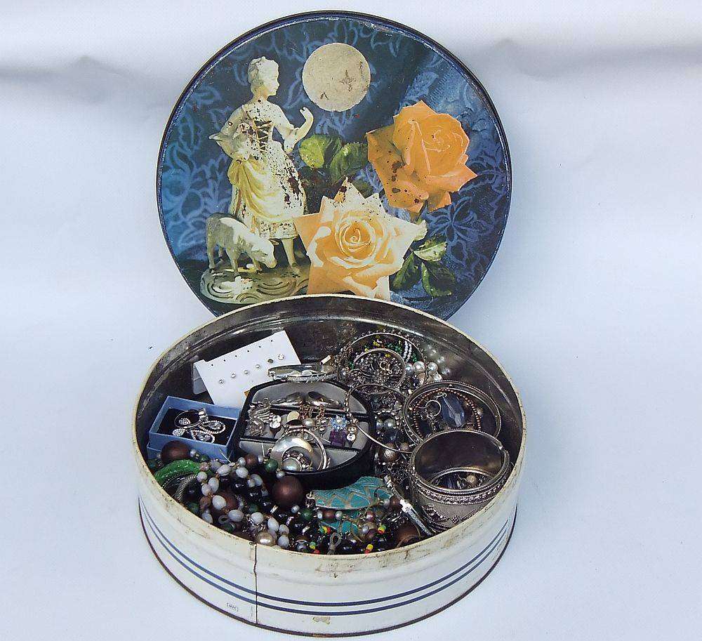 A rusty old tin filled with loads of usable jewelry and spare parts