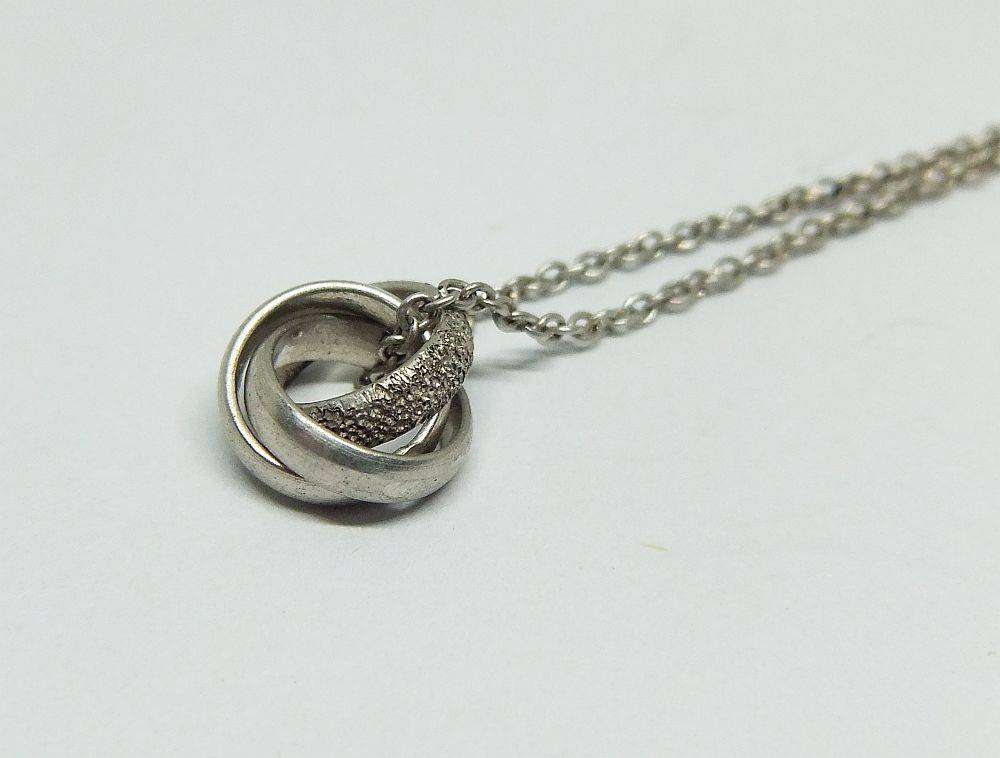 A dainty sterling silver necklace with a sterling silver triple ring pendant in good condition