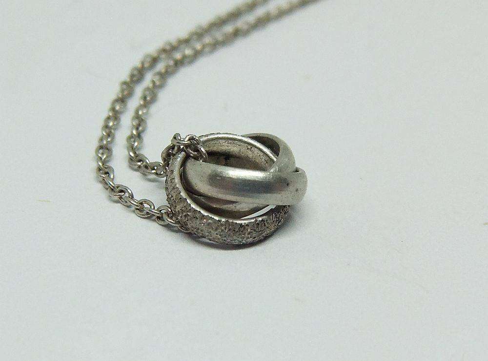 A dainty sterling silver necklace with a sterling silver triple ring pendant in good condition