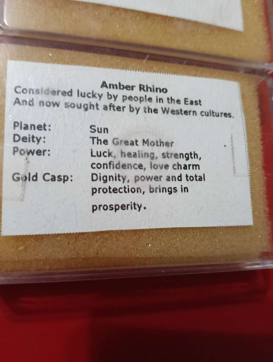 TWO AMBER AND GOLD RHINO PENDANTS.