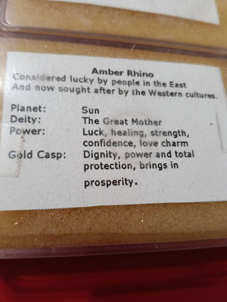 TWO AMBER AND GOLD RHINO PENDANTS.