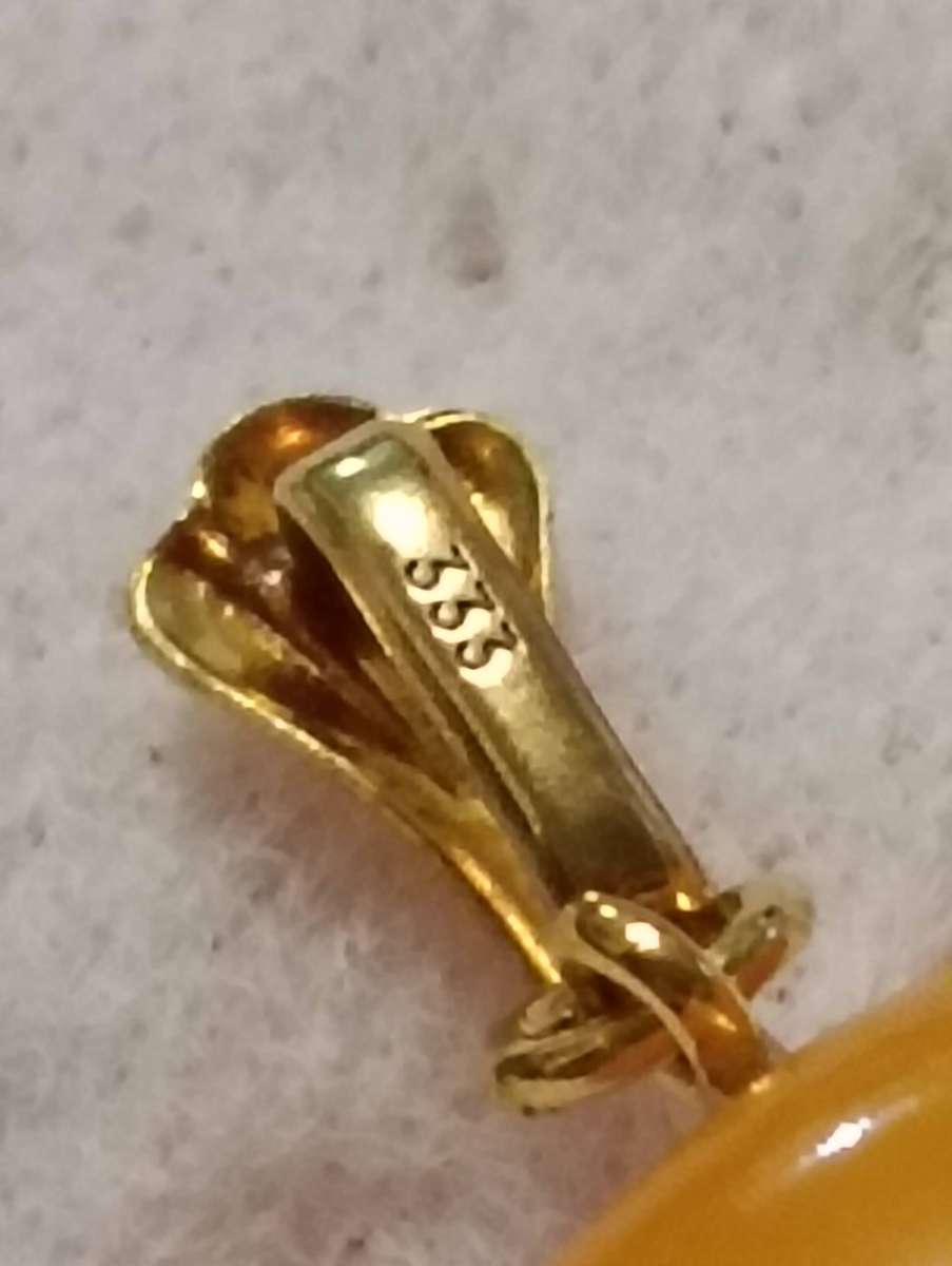 TWO AMBER AND GOLD RHINO PENDANTS.