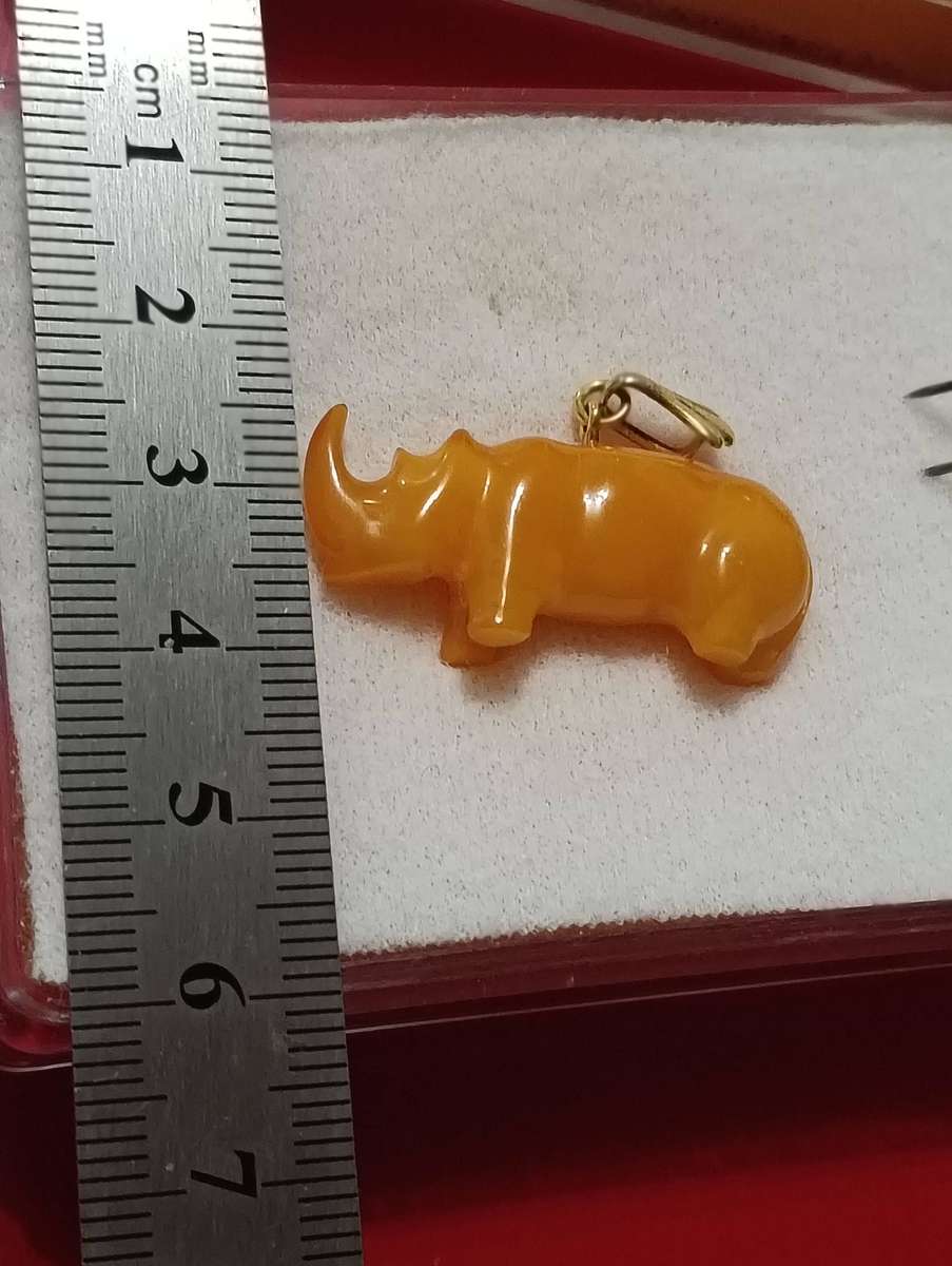 TWO AMBER AND GOLD RHINO PENDANTS.