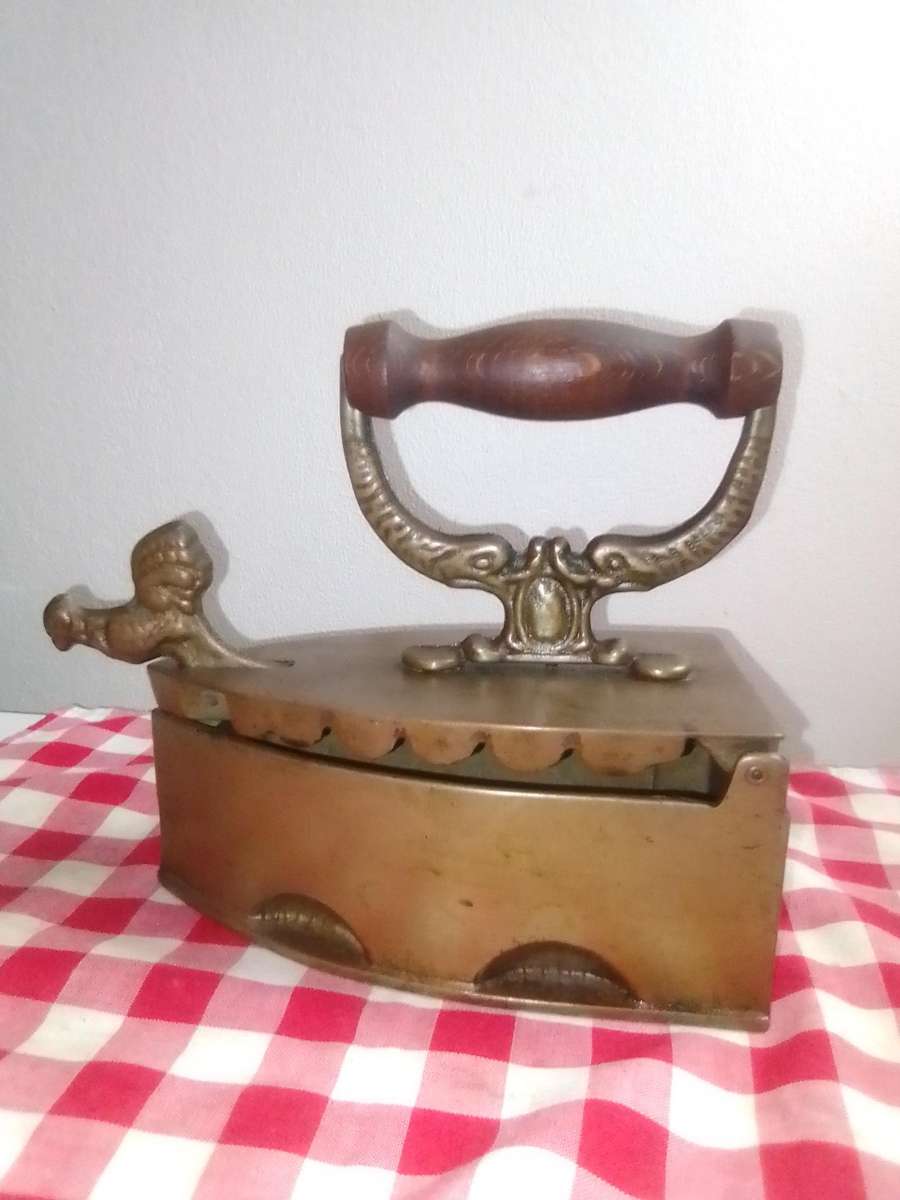 A Vintage Coal Iron in Brass metal with patrons on sides and wooden handle. In Original condition.