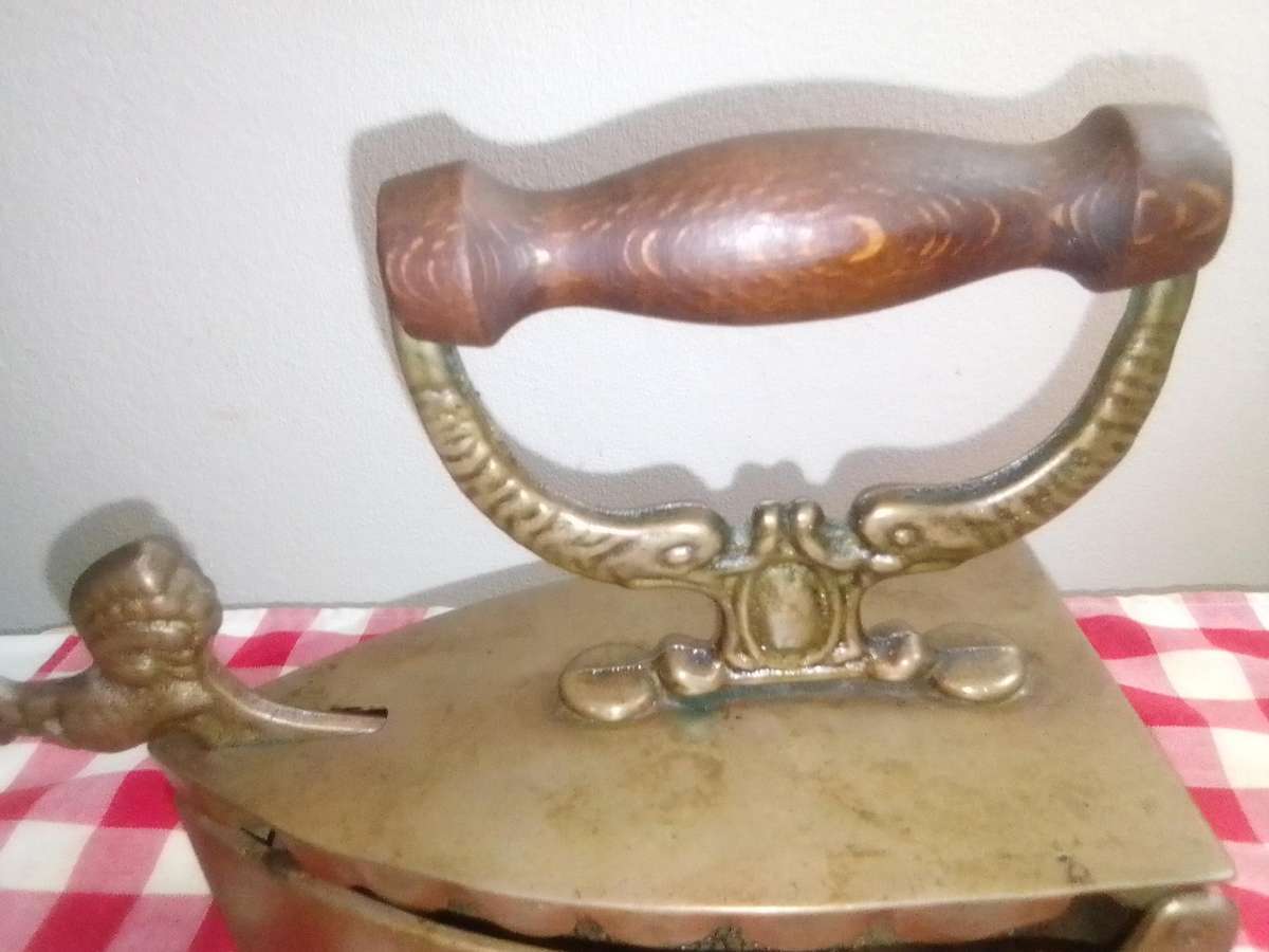 A Vintage Coal Iron in Brass metal with patrons on sides and wooden handle. In Original condition.