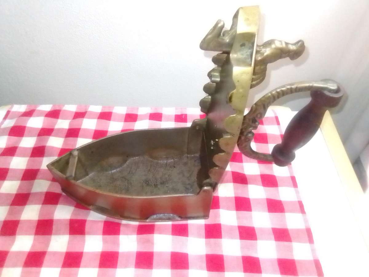 A Vintage Coal Iron in Brass metal with patrons on sides and wooden handle. In Original condition.