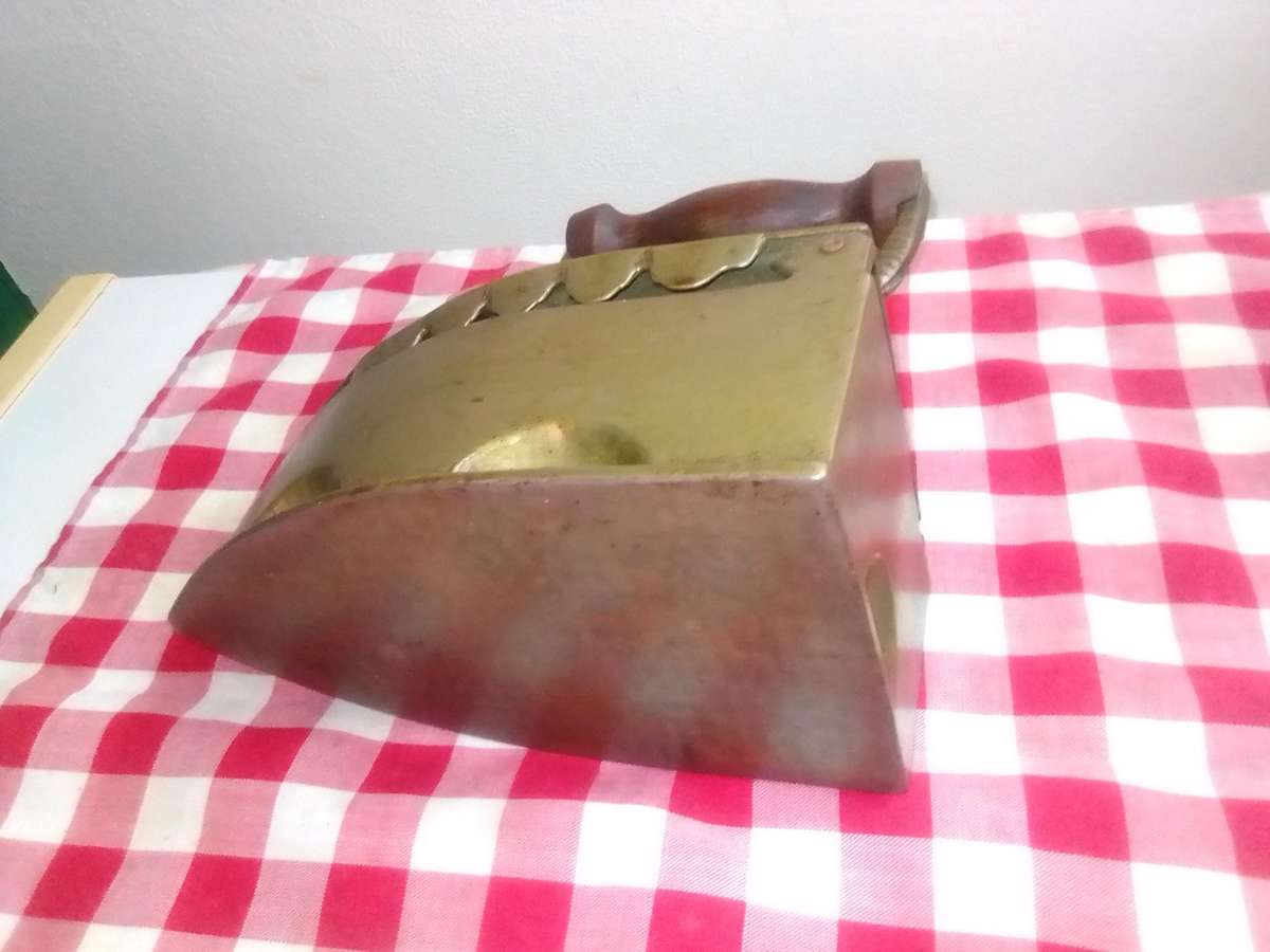 A Vintage Coal Iron in Brass metal with patrons on sides and wooden handle. In Original condition.