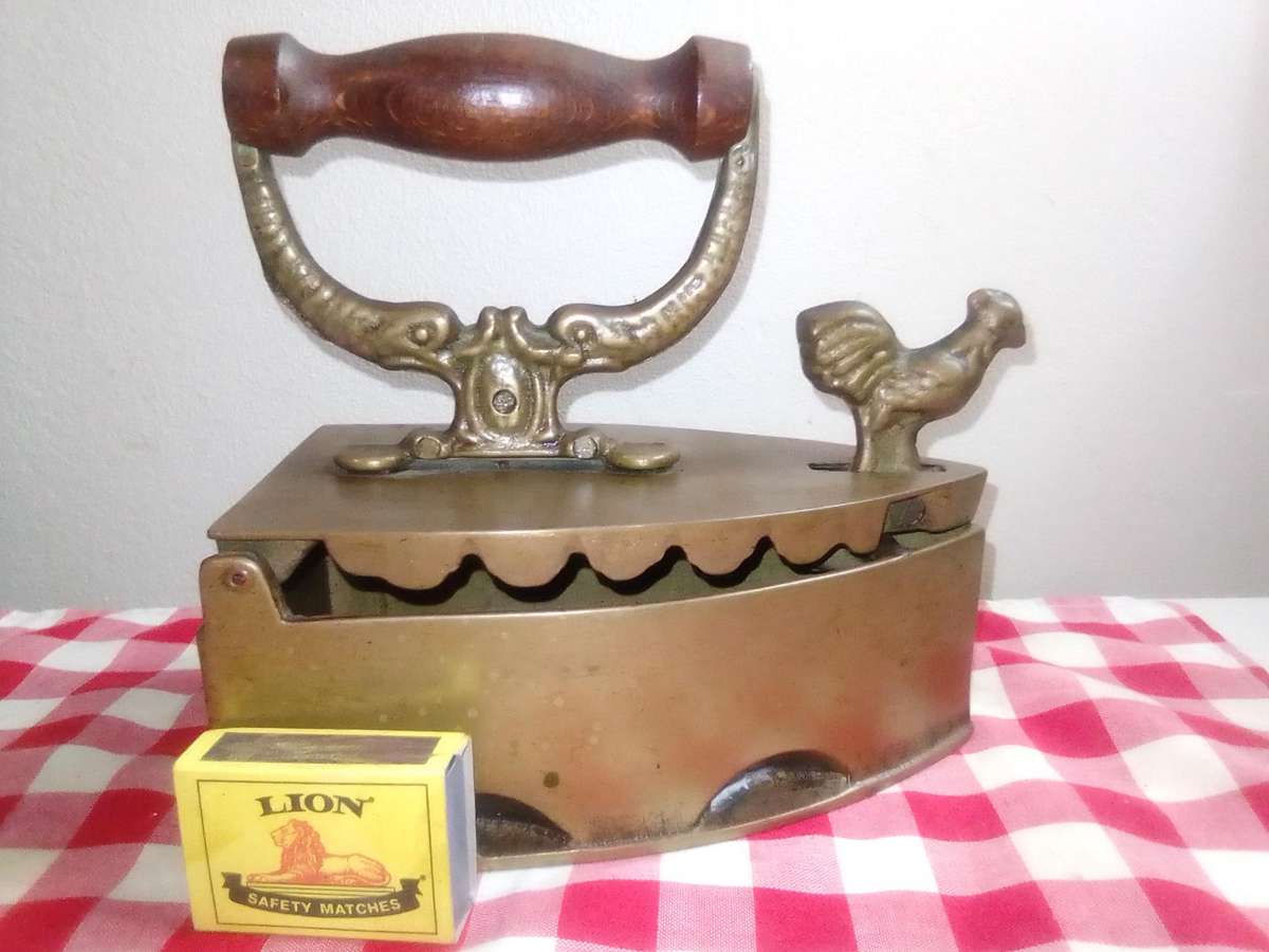 A Vintage Coal Iron in Brass metal with patrons on sides and wooden handle. In Original condition.