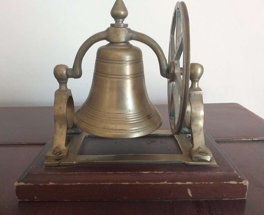 Antique brass bell mounted on wooden plate