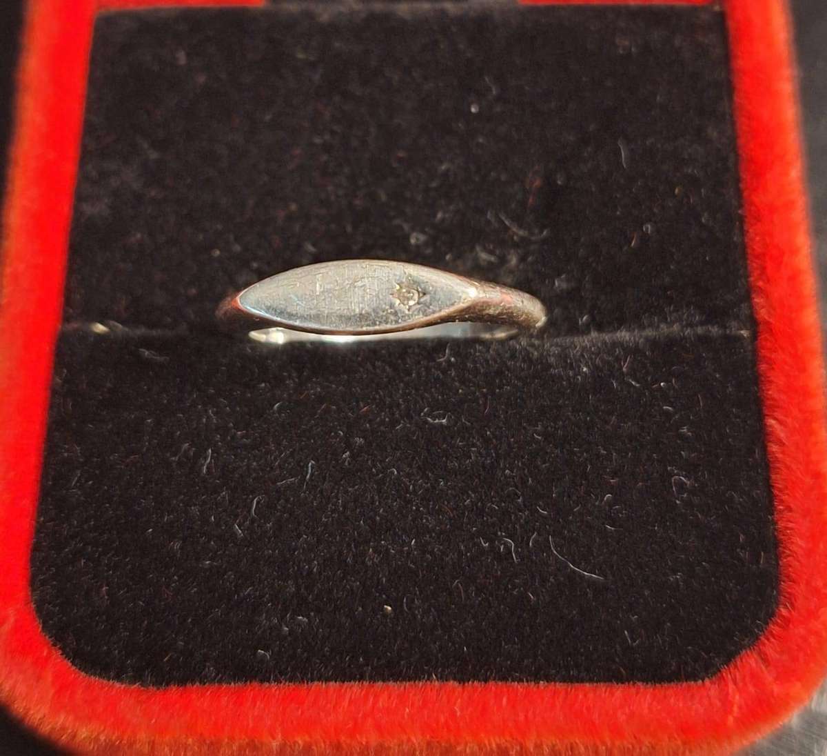 silver ring features a sleek, marquise-shaped face set with a tiny sparkling stone