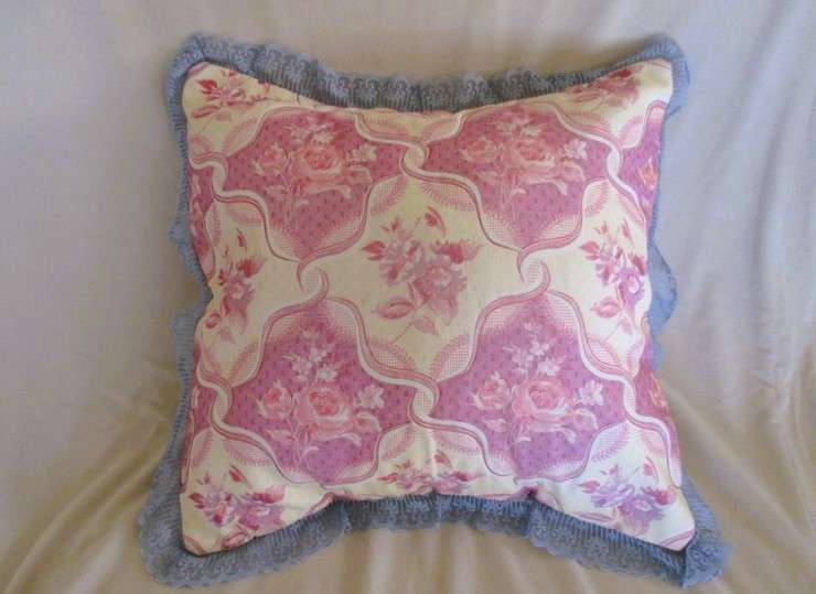 A pretty, plump cushion with floral design and lace border