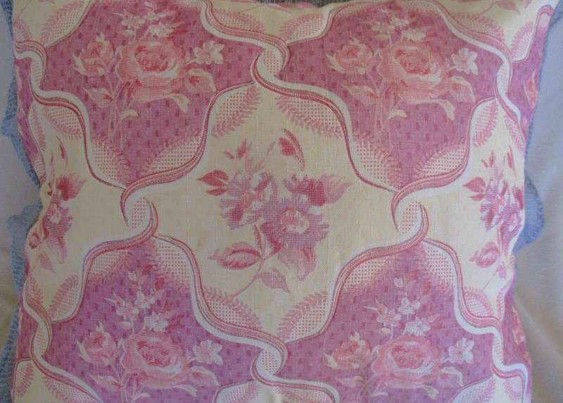 A pretty, plump cushion with floral design and lace border