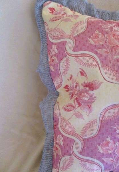 A pretty, plump cushion with floral design and lace border