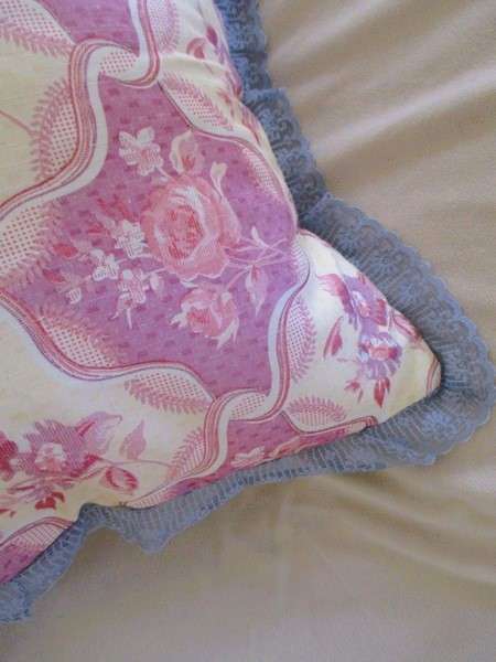 A pretty, plump cushion with floral design and lace border
