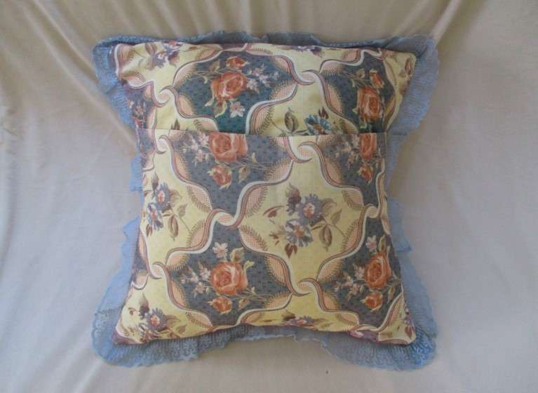 A pretty, plump cushion with floral design and lace border