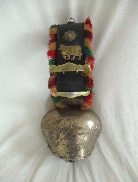 A very large vintage Swiss cow bell with ornate strap and buckle