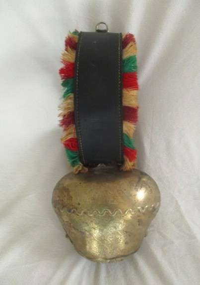 A very large vintage Swiss cow bell with ornate strap and buckle