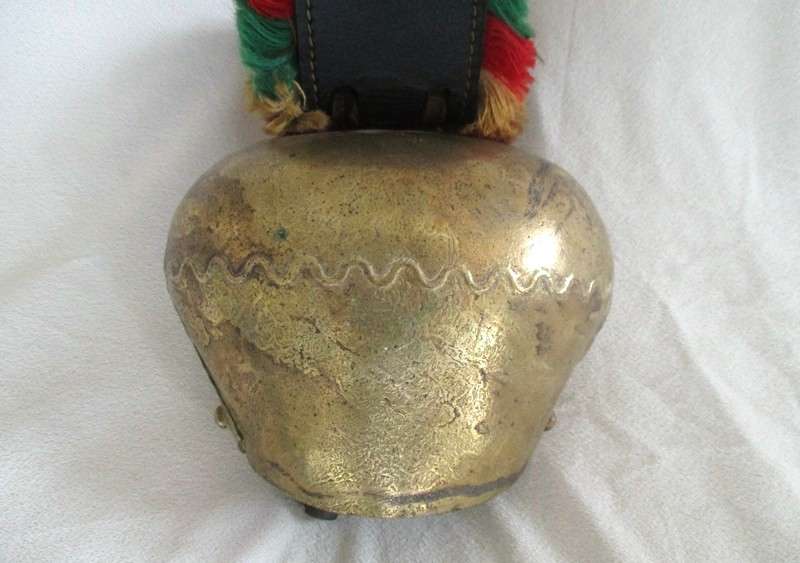 A very large vintage Swiss cow bell with ornate strap and buckle