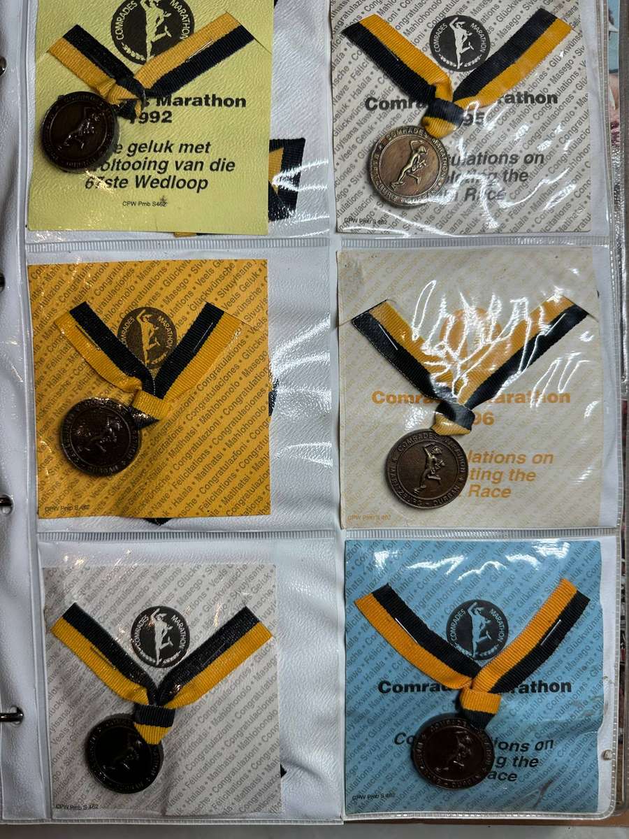 Comrades Marathon Folder with 11 medals, cloth badges etc.