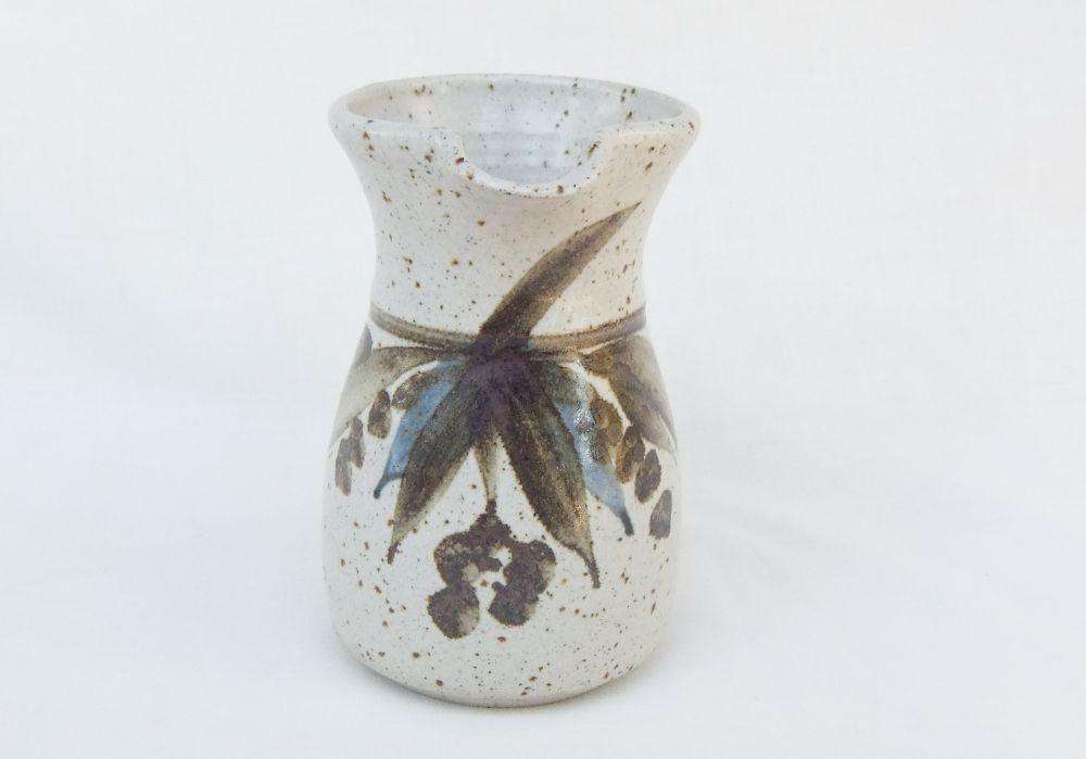 A vintage handmade pottery milk jug stamped with the makers mark