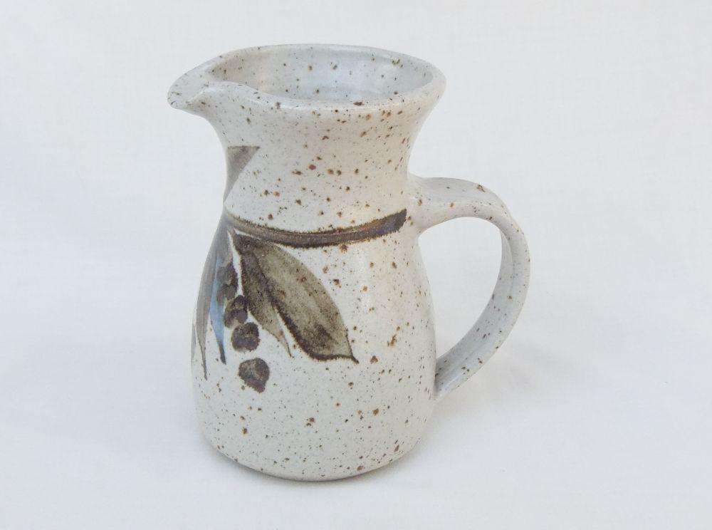 A vintage handmade pottery milk jug stamped with the makers mark