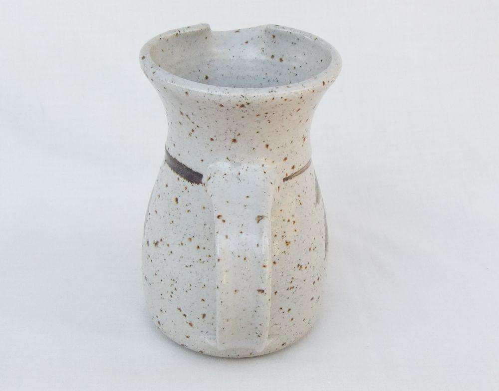 A vintage handmade pottery milk jug stamped with the makers mark