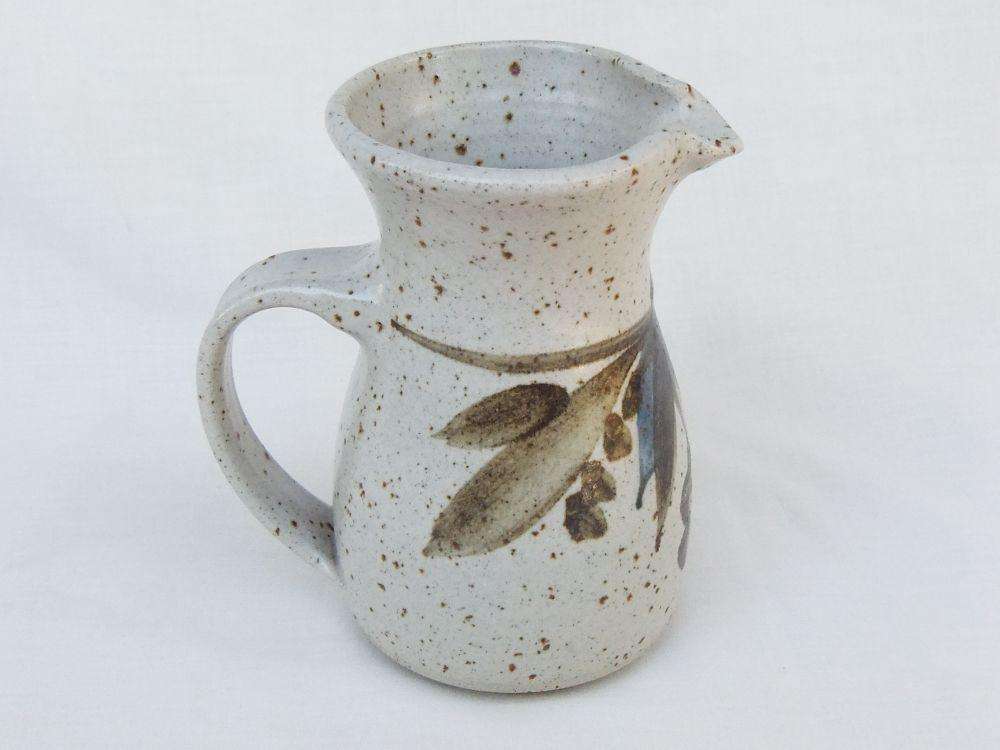 A vintage handmade pottery milk jug stamped with the makers mark