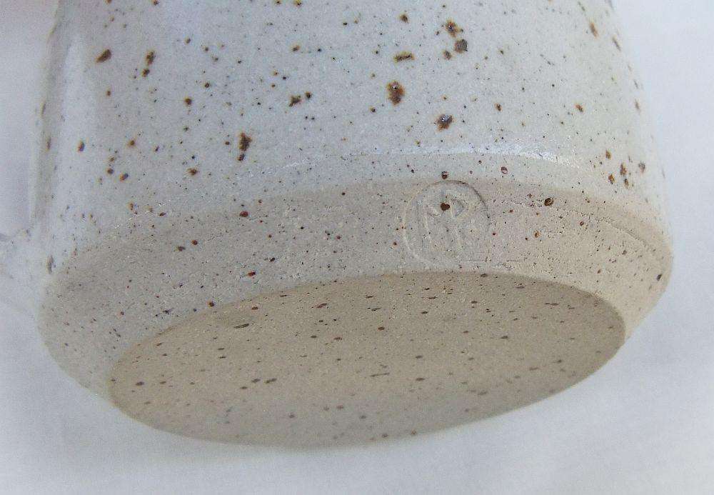 A vintage handmade pottery milk jug stamped with the makers mark