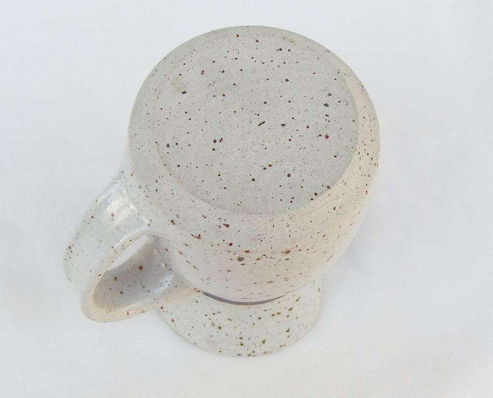A vintage handmade pottery milk jug stamped with the makers mark