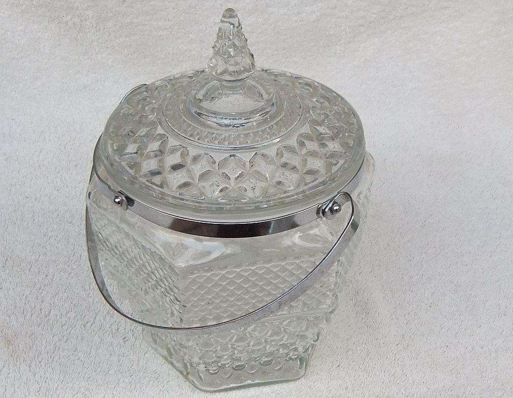 A large vintage molded glass cookie jar with metal handle