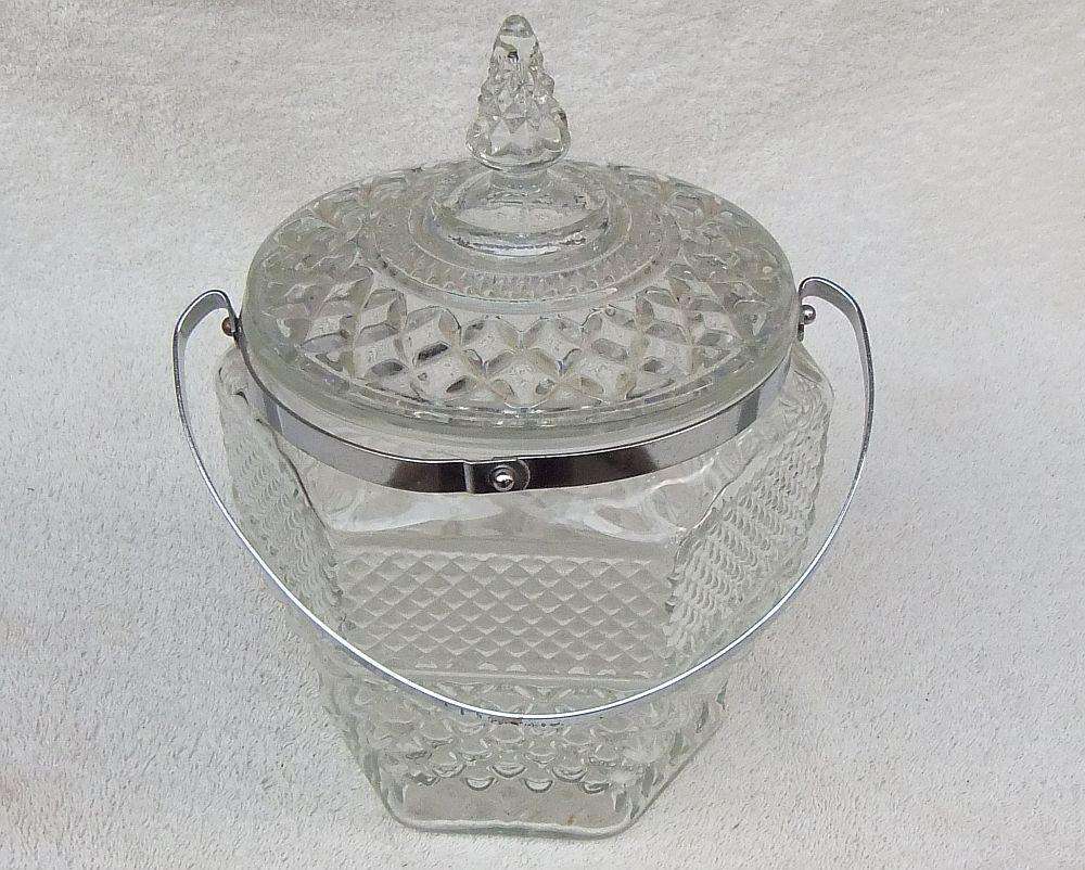 A large vintage molded glass cookie jar with metal handle