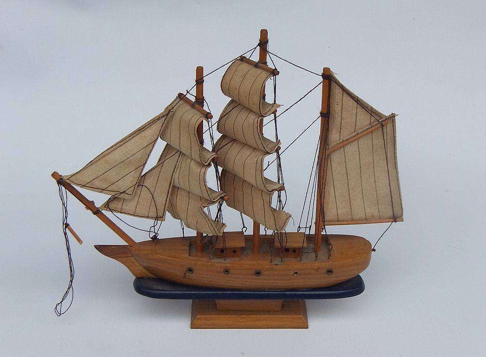 A detailed vintage wooden model of a sail ship with cloth sails