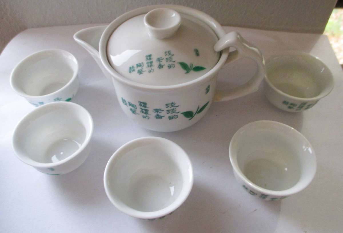 Boxed Chinese porcelain set includes a teapot and five tea cups featuring green leaf illustrations
