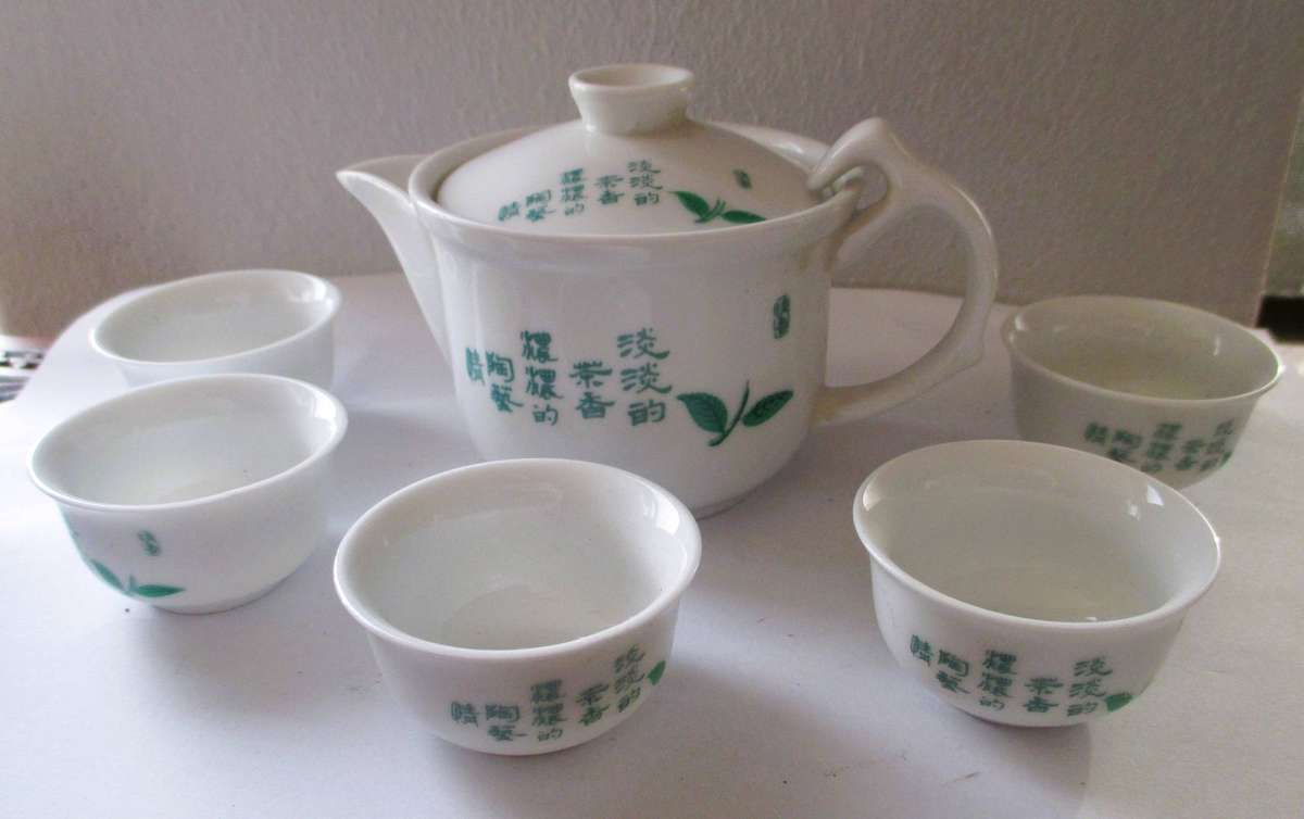 Boxed Chinese porcelain set includes a teapot and five tea cups featuring green leaf illustrations