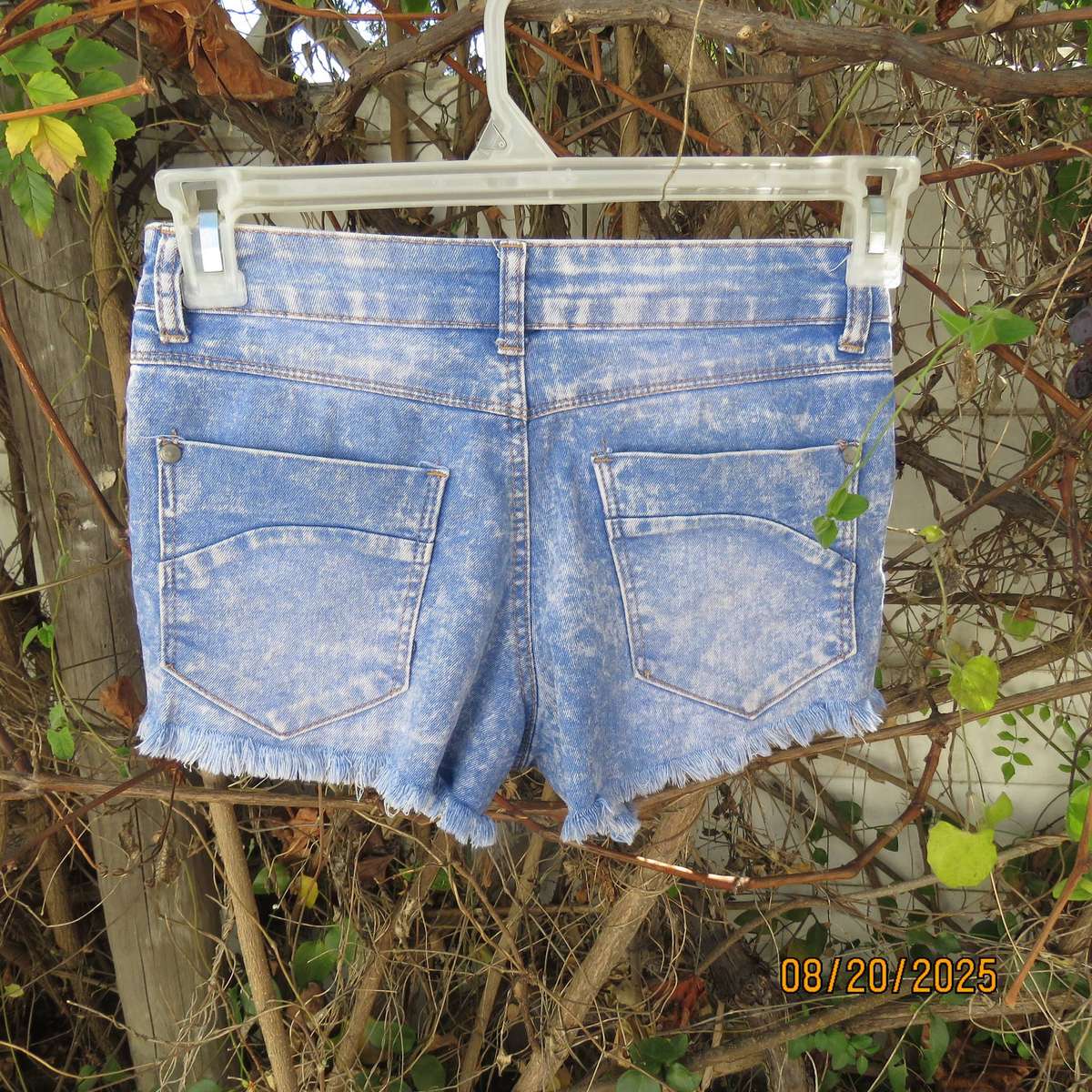 Blue denim distressed jean shorts size 30 with raw edge leg seams.