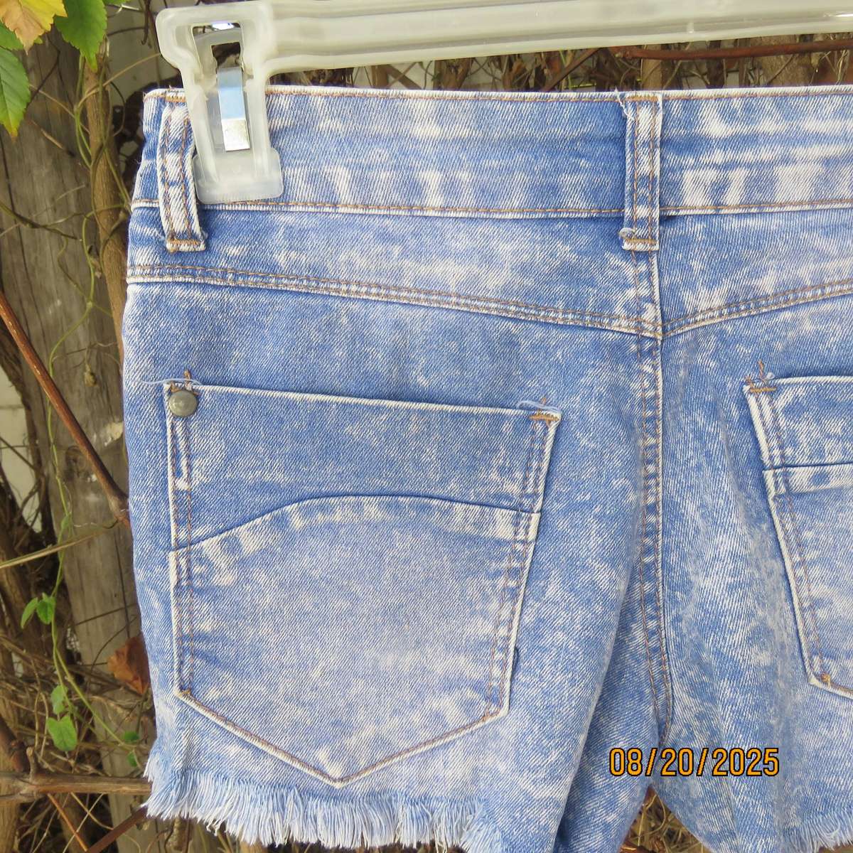Blue denim distressed jean shorts size 30 with raw edge leg seams.
