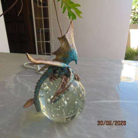 Decorative blue and gold fantasy dragon figurine perched on glass bubble ball