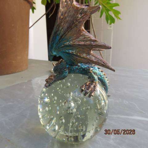 Decorative blue and gold fantasy dragon figurine perched on glass bubble ball