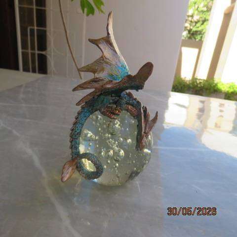Decorative blue and gold fantasy dragon figurine perched on glass bubble ball