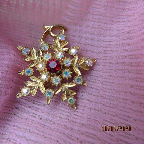 Gold toned floral brooch with ruby red stone and crystal accents