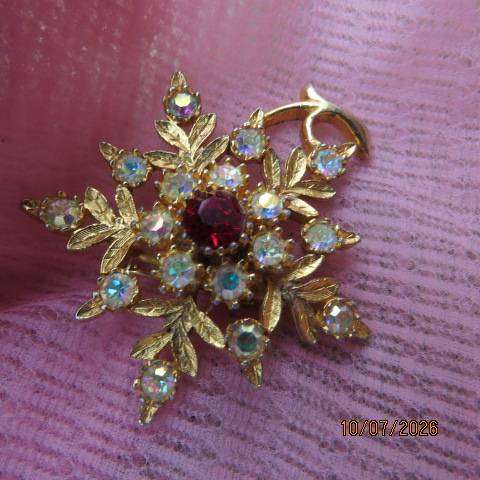 Gold toned floral brooch with ruby red stone and crystal accents