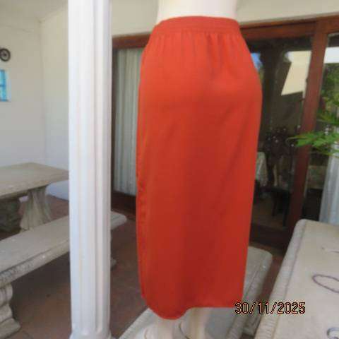 Burnt orange ankle length polyester skirt with front button decoration. Elastic waistband. Size 40